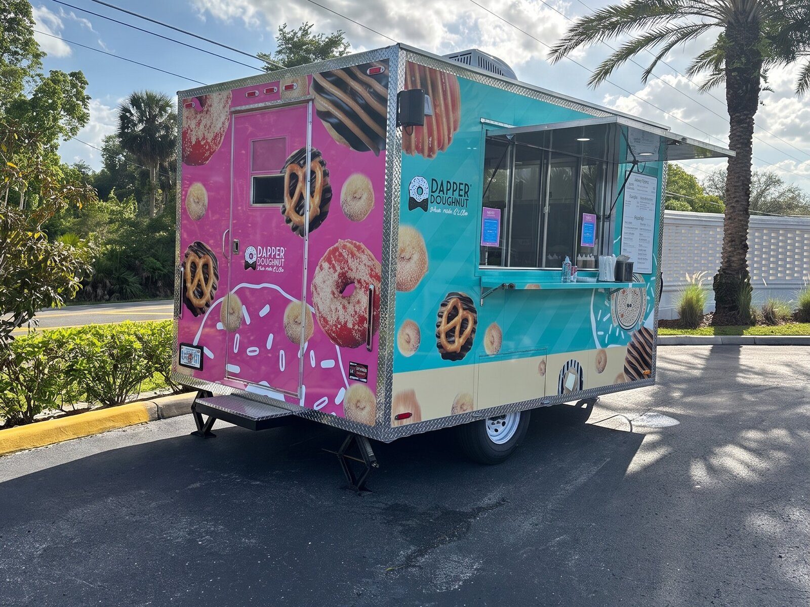 Branded pink and teal Dapper Doughnut food trailer parked at an event